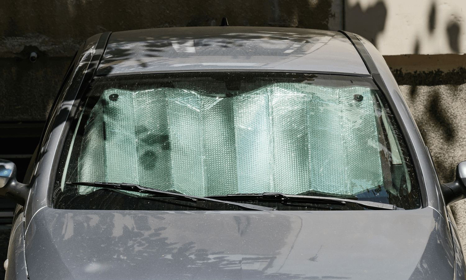 Das Auto wird mit einem Sonnenschutz für die Windschutzscheibe vor zu viel Sonneneinstrahlung geschützt. © iStock