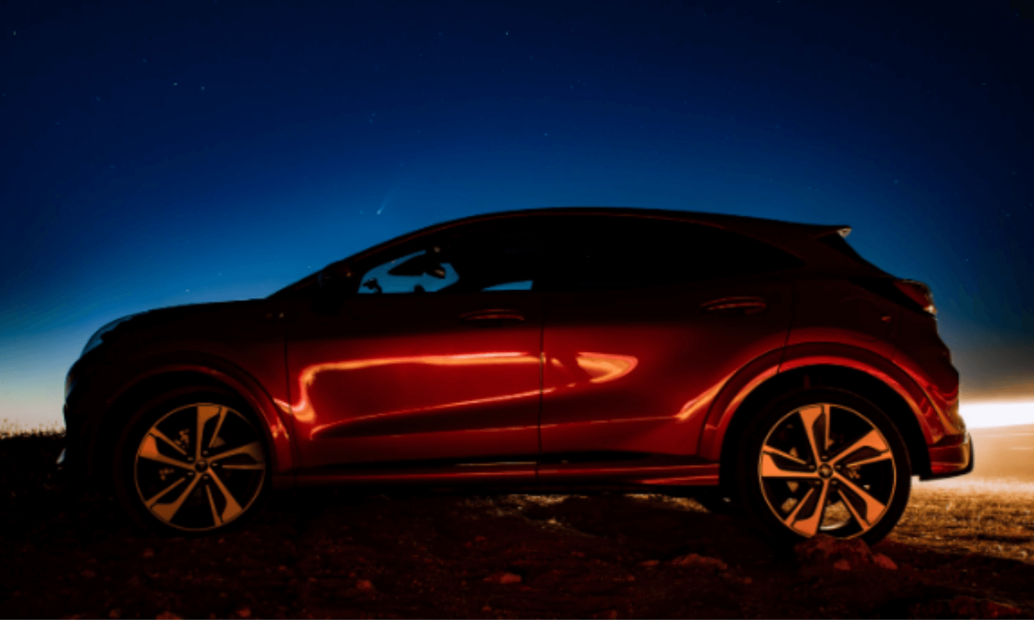 Ein roter Ford Puma wird wurde vor dem Nachthimmel fotografiert. © iStock.com