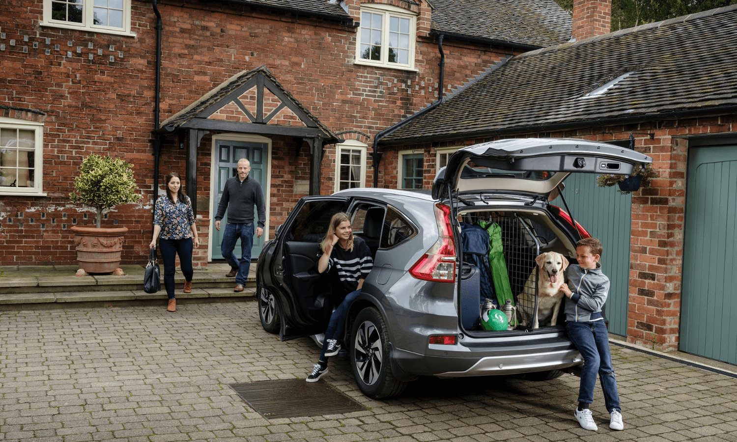Eine Familie belädt das Auto für einen Ausflug mit Hund in den Wald. © Travall