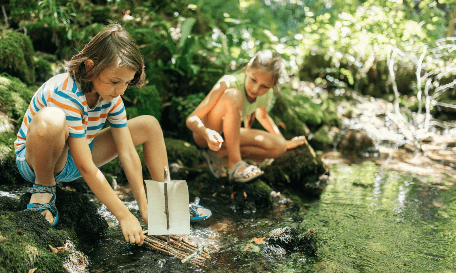 Die Kinder bauen ein Floß und lassen es am Bach schwimmen. © iStock.com