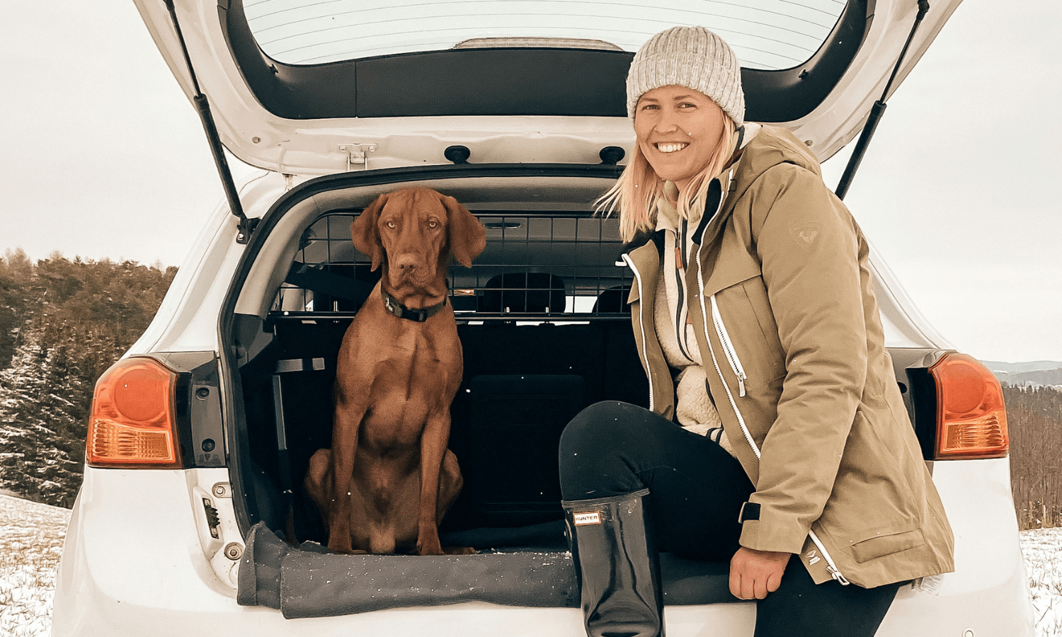 Der Hund wird im Kofferraum mit einem Travall Guard Hundegitter gesichert. Zusammen mit seiner Besitzerin freut er sich auf den Ausflug in die verschneite Natur. © Travall