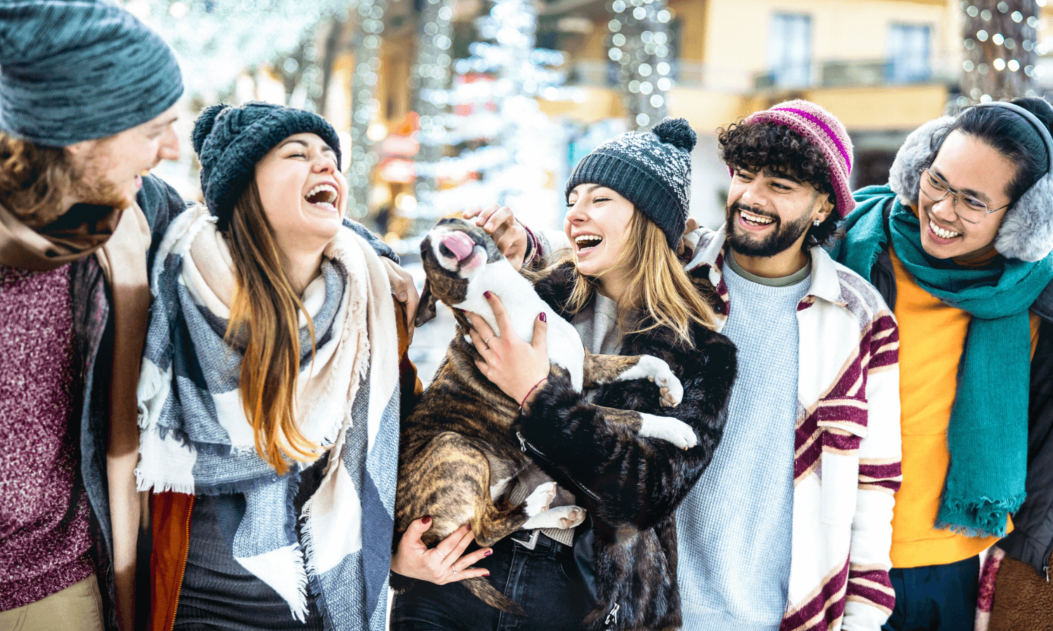 Auf dem Hundeweihnachtsmarkt kann man sich mit anderen Hundebesitzern treffen. Die Personen auf dem Foto lachen. Ein Hund ist auch dabei. © iStock