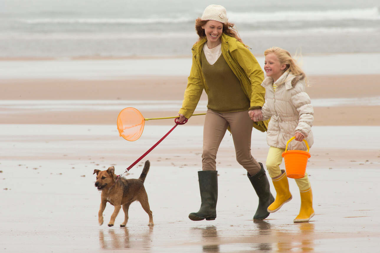 Mother and daughter on beach with dog