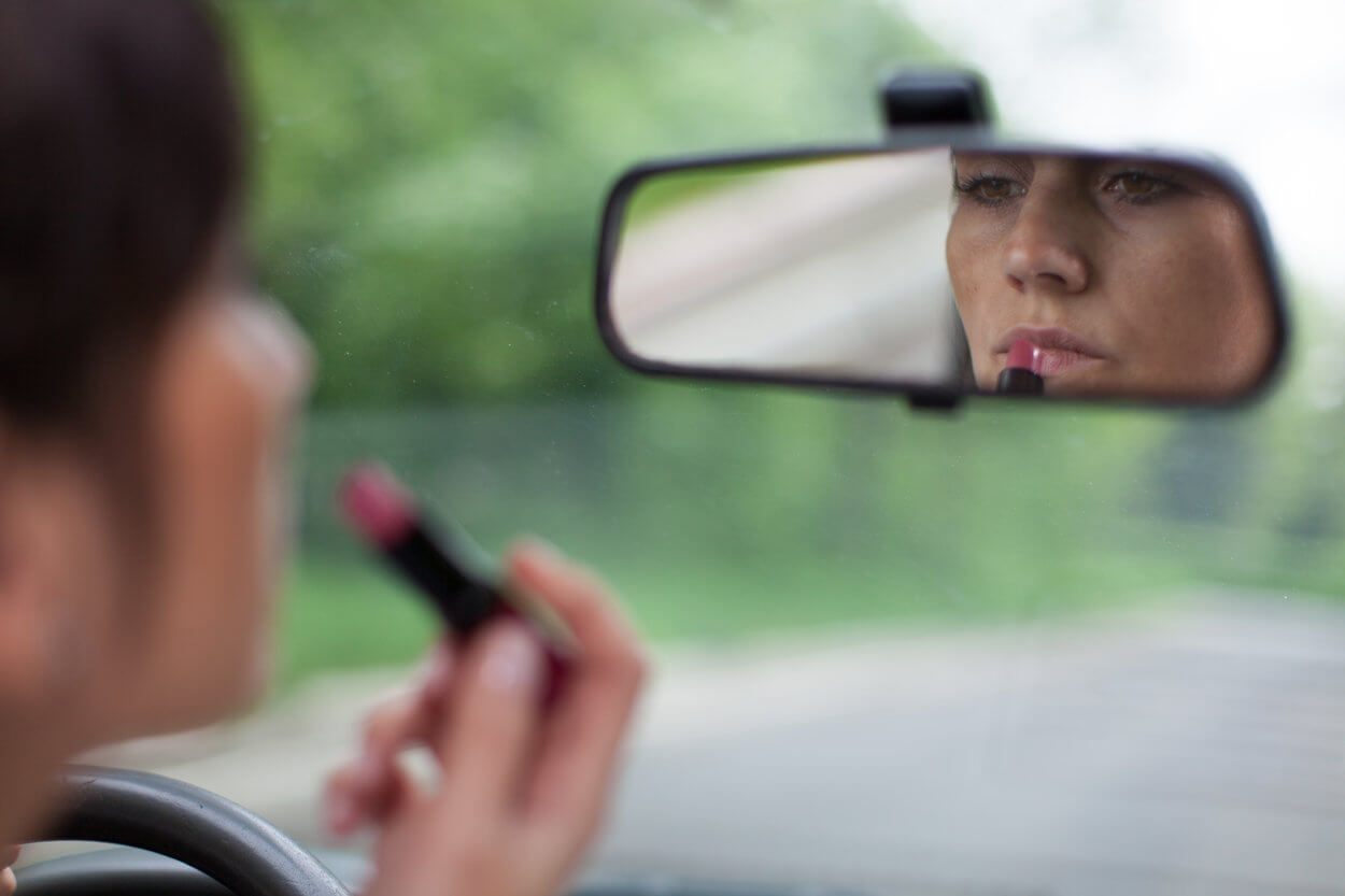 Woman applying lipstick while driving her car