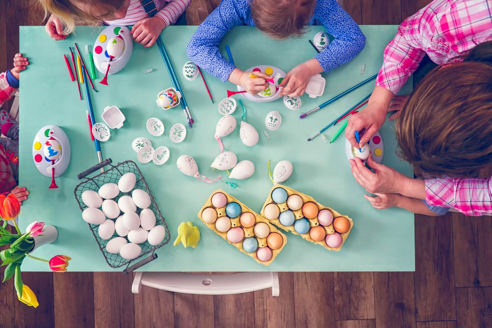 little kids having fun with coloring Easter eggs with various colors.