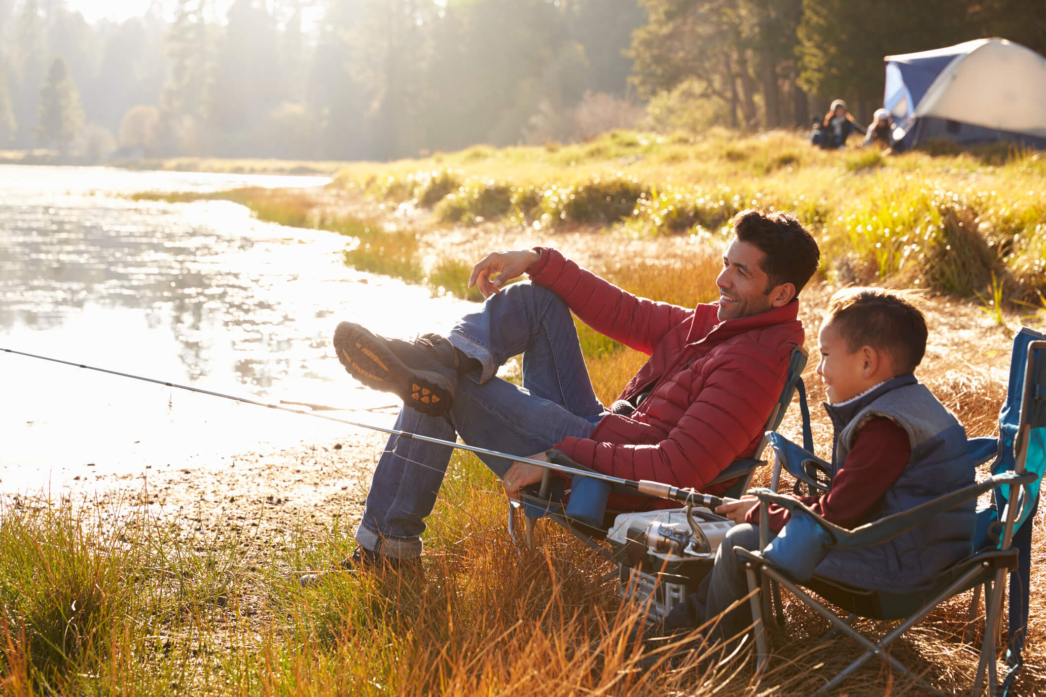 Father and son on a camping trip fishing by a lake