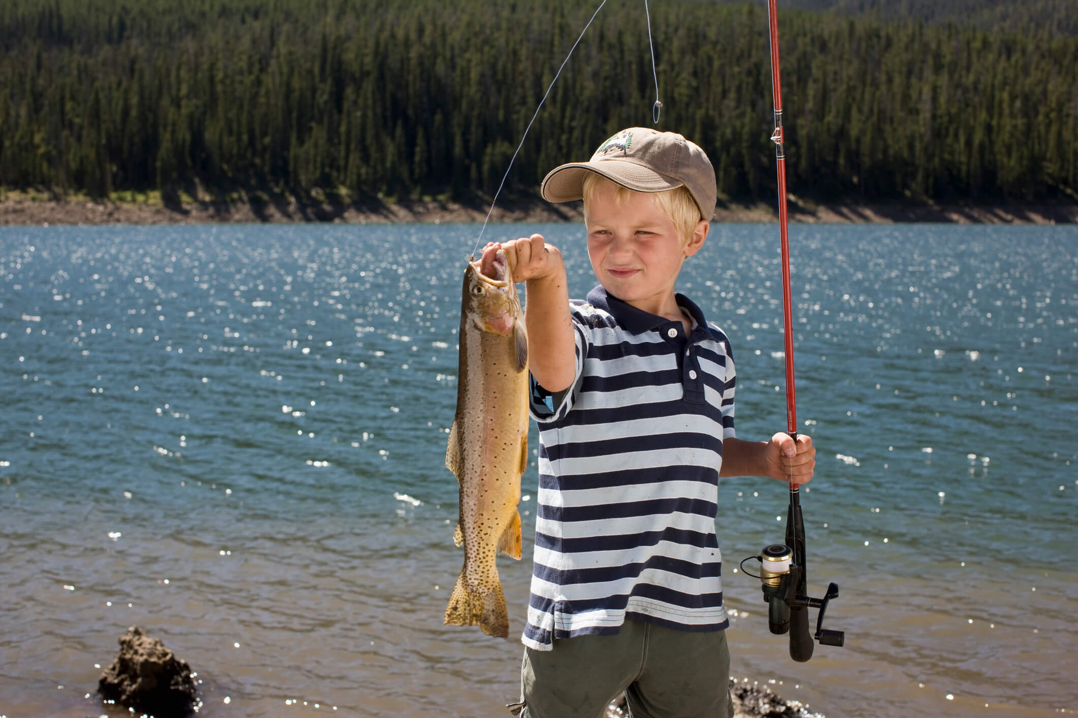 Boy looking a fish he just caught by lakeside